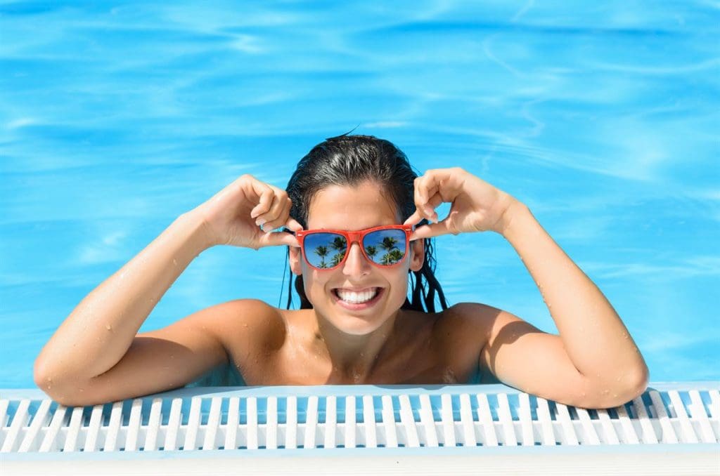 Happy woman enjoying pool in tropical resort on summer