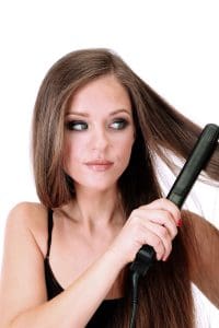 Woman doing hairstyle with hair straightener, isolated on white