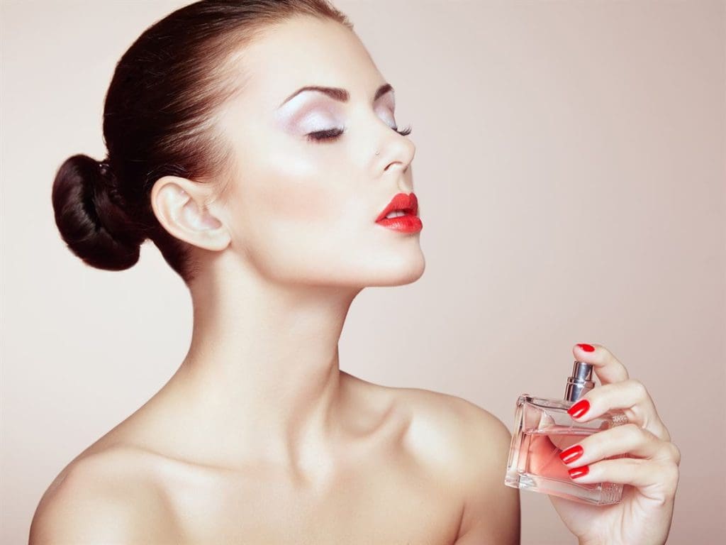 Young beautiful woman with bottle of perfume. Perfect Makeup