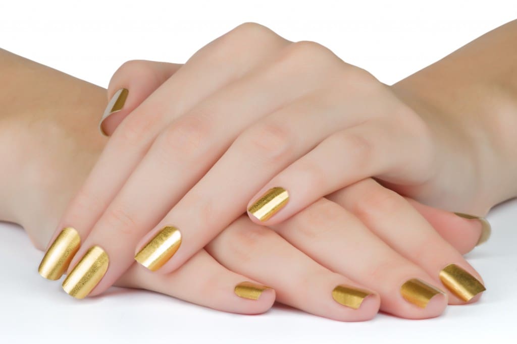 Manicured golden woman nails on the table close up